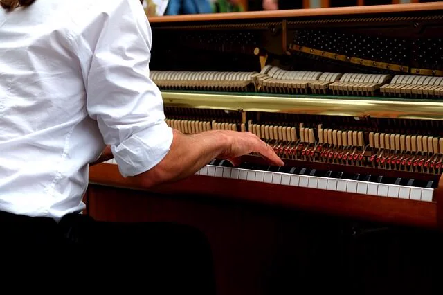Técnico frente a un piano vertical abierto, con la mecánica a la vista