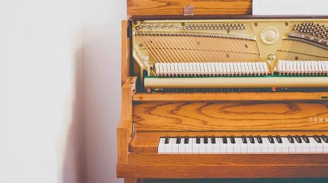 Piano vertical de madera abierto, con la mecánica a la vista