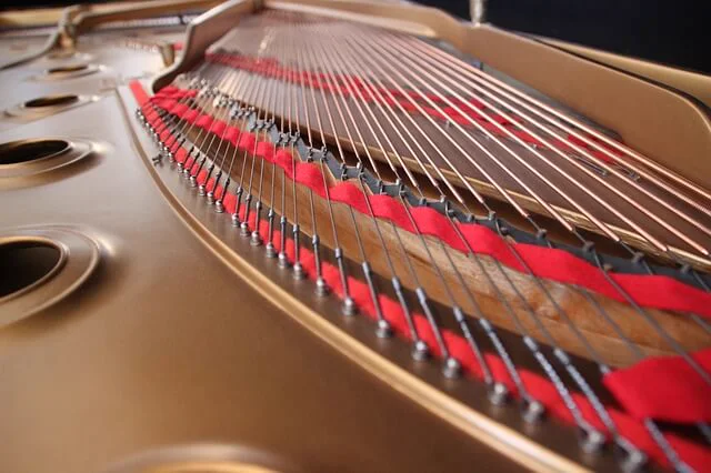 Interior dorado de un piano de cola con el fieltro rojo entre las cuerdas