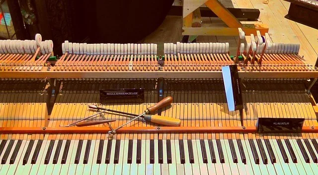 Banco de trabajo con la mecánica de un piano desarmada y herramientas