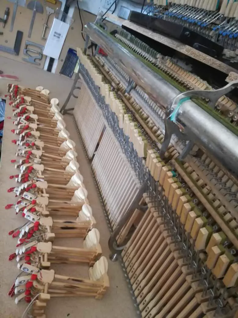 Taller con mesas de trabajo, mecánicas de piano y herramientas